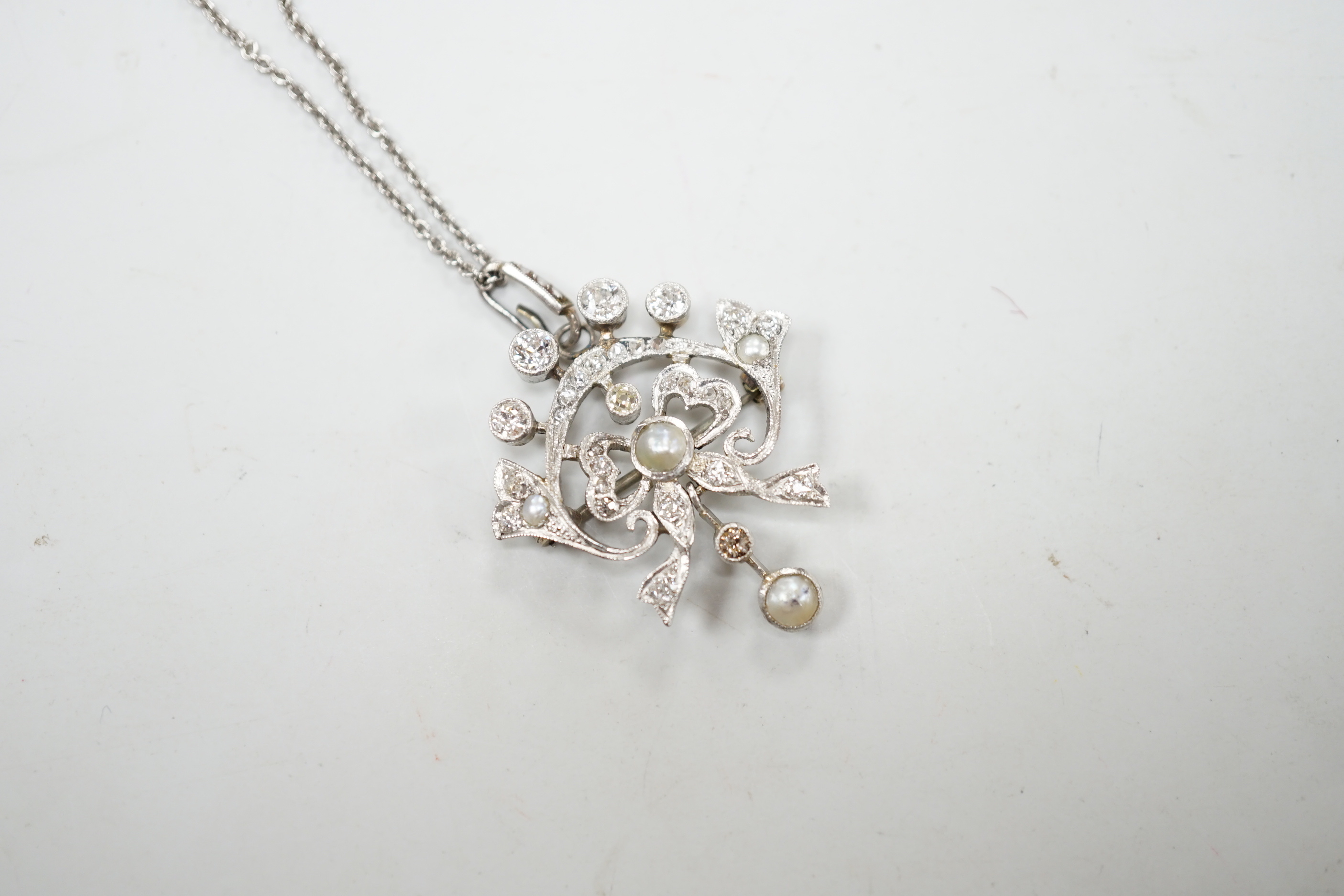 An early 20th century white metal, millegrain set diamond and split pearl cluster set drop pendant/brooch, overall 37mm, gross 5.8 grams, on a later sterling chain.